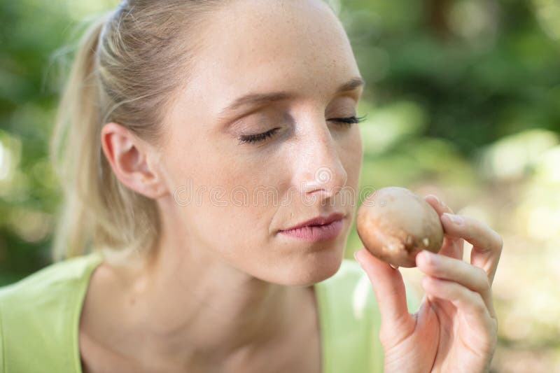 Woman smelling earthy mushrooms stock image