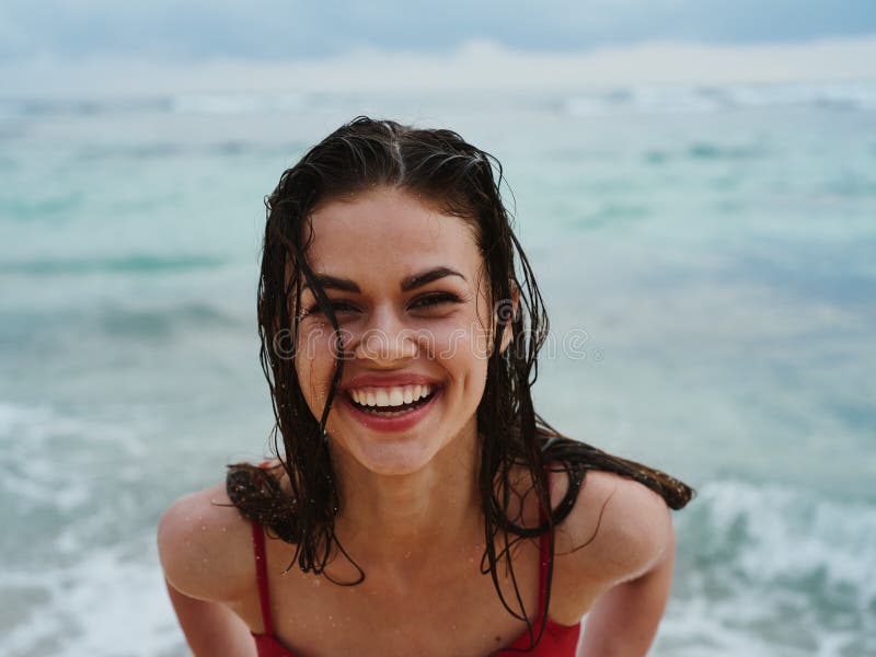 Woman Smile With Teeth Tourist In Red Swimsuit Sitting On The Sand On The Beach In The Ocean In