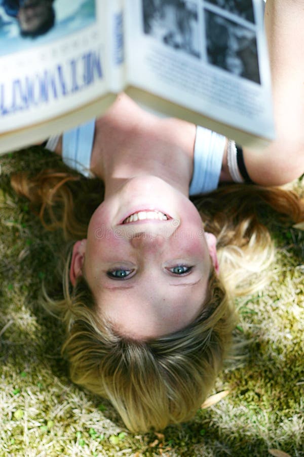 Young woman smiling as she reads a book outdoors. Young woman smiling as she reads a book outdoors