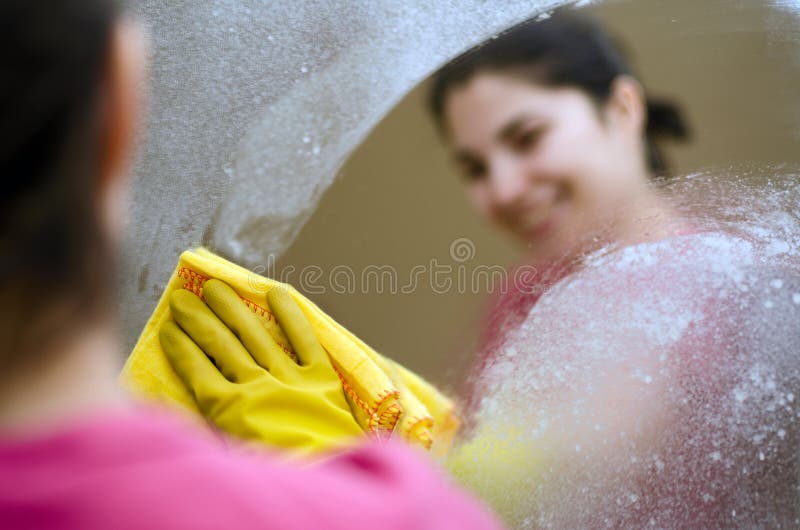 Una mujer limpieza Espejo agotador goma guantes.