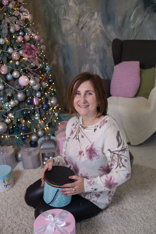 Woman smiling near christmas tree and holding a present stock images