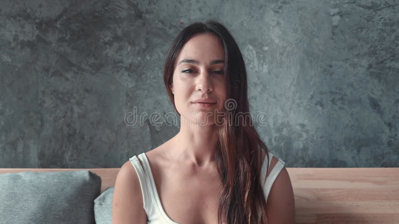 Woman on sofa gazes confidently into camera her poise and beauty striking Woman's look conveys strength and