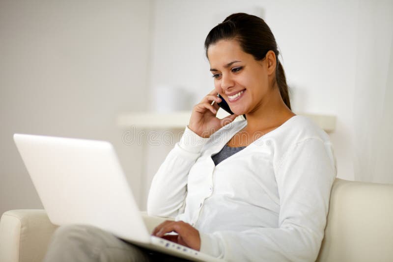 Portrait of a woman speaking on cellphone in front of her laptop computer at home. Portrait of a woman speaking on cellphone in front of her laptop computer at home