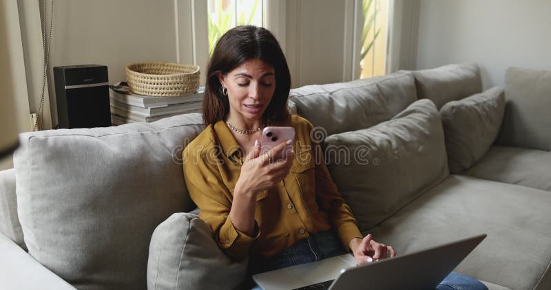 Woman speaks on speakerphone while using her laptop stock video