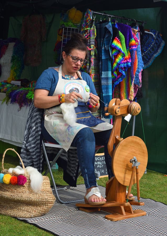 This Woman In Action Is Making Homemade Yarn With A Spinning Wheel From Raw  Wool For A Unique Hand Crafted Work. Shot In A Beautiful Garden Setting.  Stock Photo, Picture and Royalty