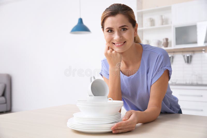 Woman with stack of clean dishes at kitchen table. royalty free stock photos Woman with stack of clean dishes at kitchen table. royalty free stock photos
