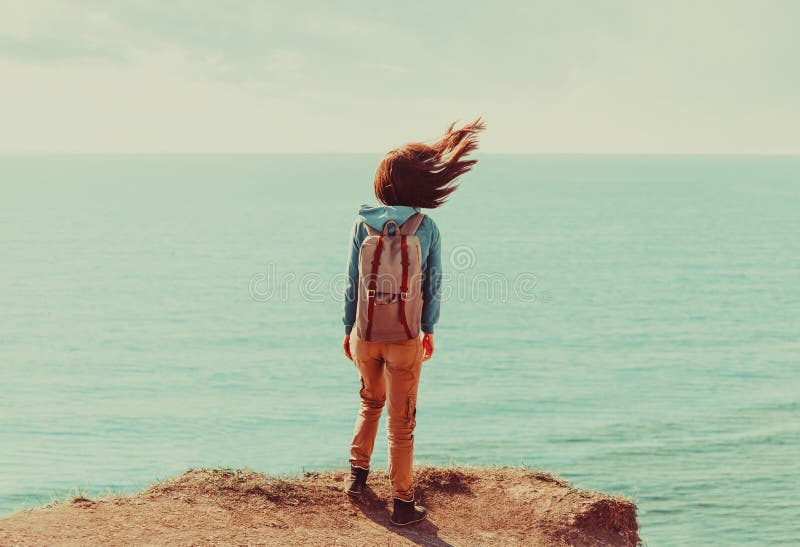 Woman standing on coastline in windy weather stock photo Woman standing on coastline in windy weather stock photo