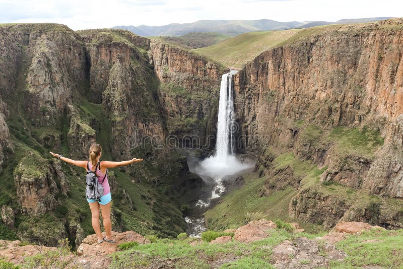 Woman standing next to stunning waterfall running down a steap canyon royalty free stock photography Woman standing next to stunning waterfall running down a steap canyon royalty free stock photography