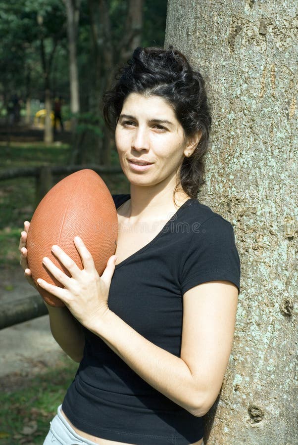 Woman Standing Next to Tree Holding a Footba