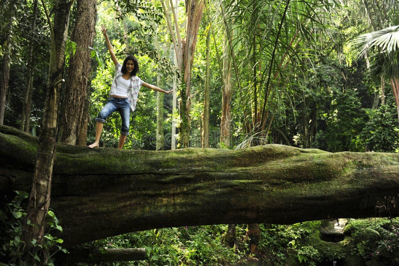 Woman standing on a tree in a tropical forest