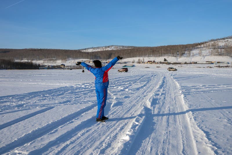 A woman stands, holding up her hands, in a winter lake against the backdrop of the shore and fishermen. stock image A woman stands, holding up her hands, in a winter lake against the backdrop of the shore and fishermen. stock image