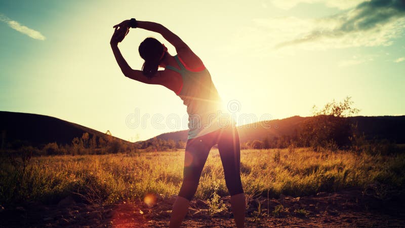 Woman stretching arms before run on sunset forest