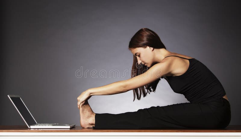 Balance at work: Young pretty woman in black sitting in front of laptop and stretching her legs . Balance at work: Young pretty woman in black sitting in front of laptop and stretching her legs .