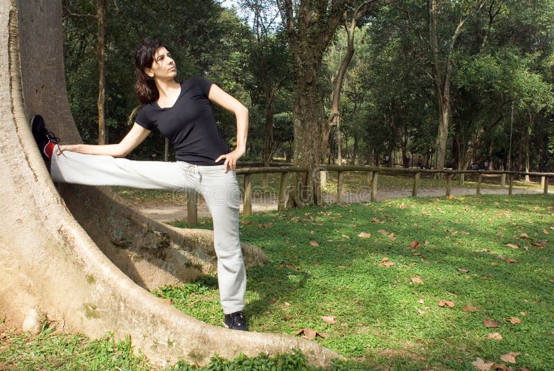 Woman Stretching Her Legs Against Tree-Horizontal