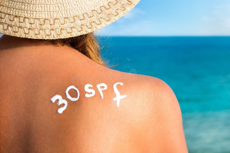 Woman with sun tan cream on her back over sea background