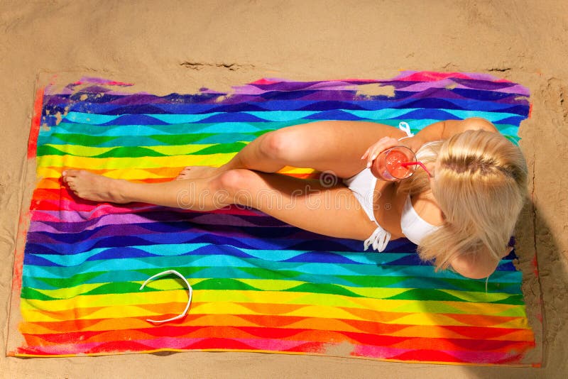 Woman sunbathing and drinking a cocktail on the be stock photo Woman sunbathing and drinking a cocktail on the be stock photo