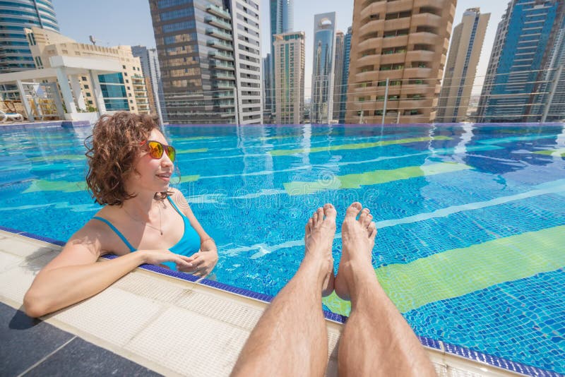 Woman is sunbathing in the pool next to her boyfriend hairy male legs
