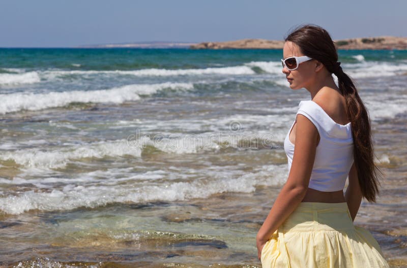 Woman in sunglasses is looking to the sea