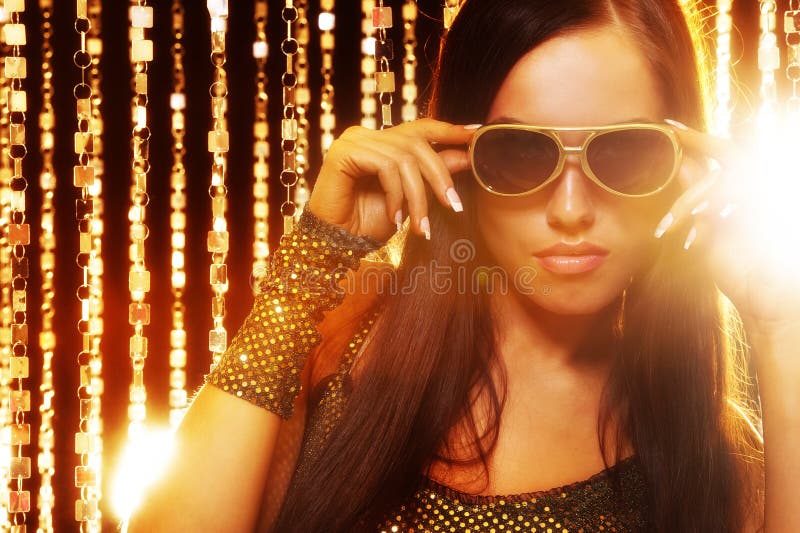 Woman in sunglasses over golden curtains