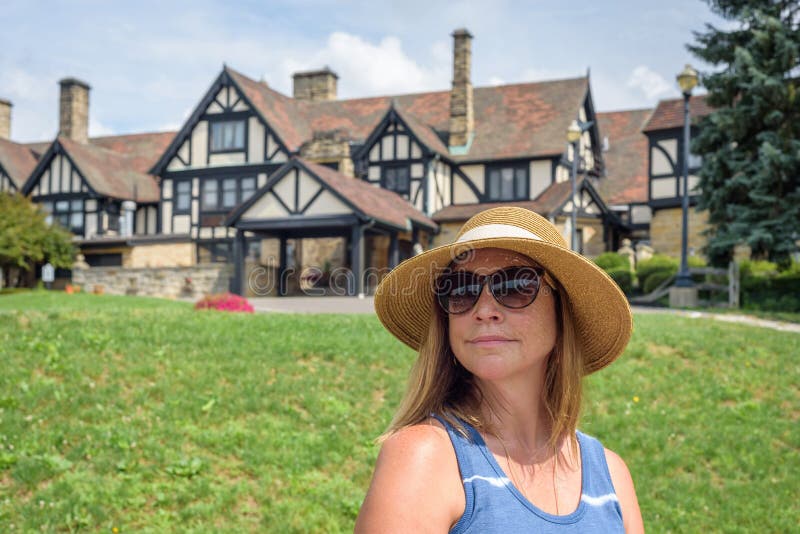 Woman in sunhat sitting in front of tudor style mansion