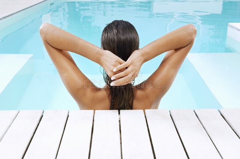 Woman In Swimming Pool At Poolside Pulling Back Hair