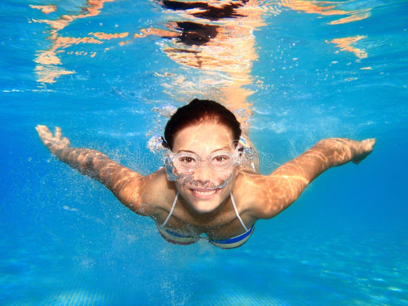 Woman swimming underwater in pool stock image
