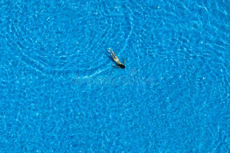 Woman swims in a swimming pool. View from above.