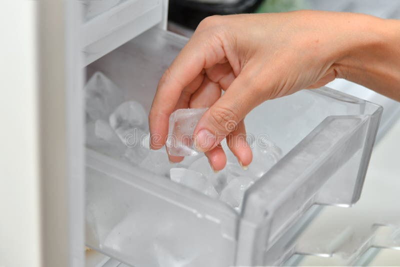 A Woman Opens An Ice Maker Tray In The Freezer To Take Ice Cubes To Cool  Drinks. Stock Photo, Picture and Royalty Free Image. Image 147627293.