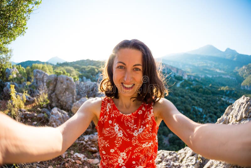 A woman takes a selfie on top of a mountain, a girl is photographed against a background of a mountain valley, a trip to the picturesque places of Turkey