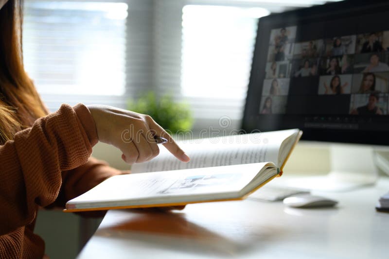 Woman taking notes during a virtual meeting while looking at a computer screen stock images