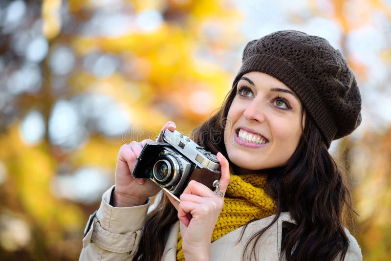 Woman taking photo with retro camera in autumn