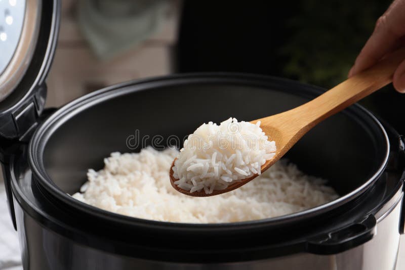 Woman taking tasty rice with spoon from cooker in kitchen royalty free stock image Woman taking tasty rice with spoon from cooker in kitchen royalty free stock image
