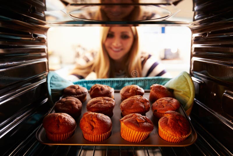 Woman Taking Tray Of Baked Muffins Out Of The Oven royalty free stock photo Woman Taking Tray Of Baked Muffins Out Of The Oven royalty free stock photo