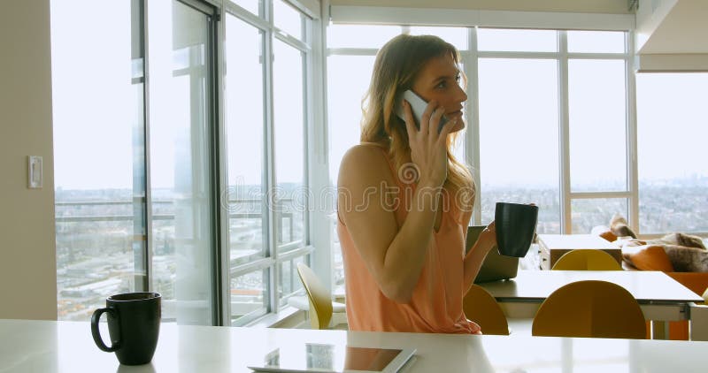 Woman talking on mobile phone while having coffee 4k