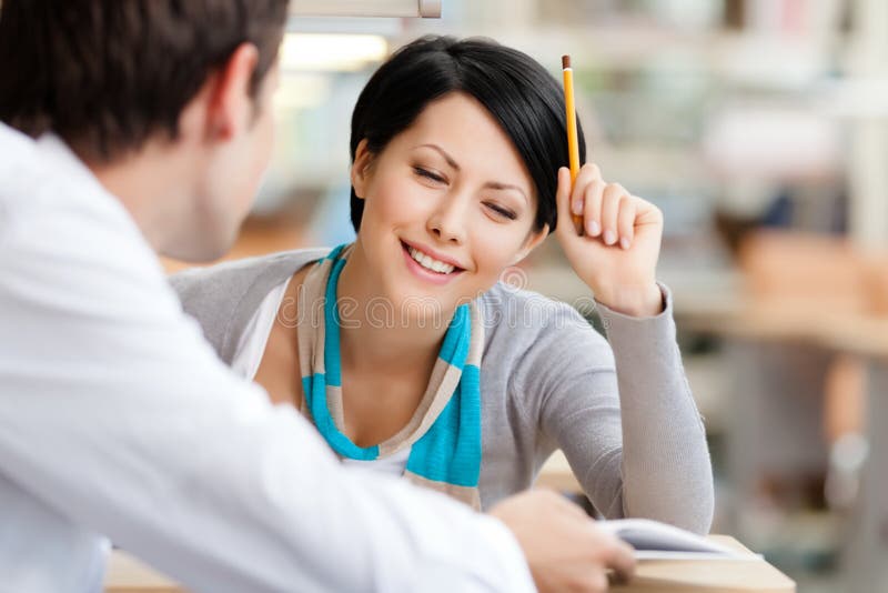 Woman communicates with handsome men showing her something in the book at the library. Woman communicates with handsome men showing her something in the book at the library