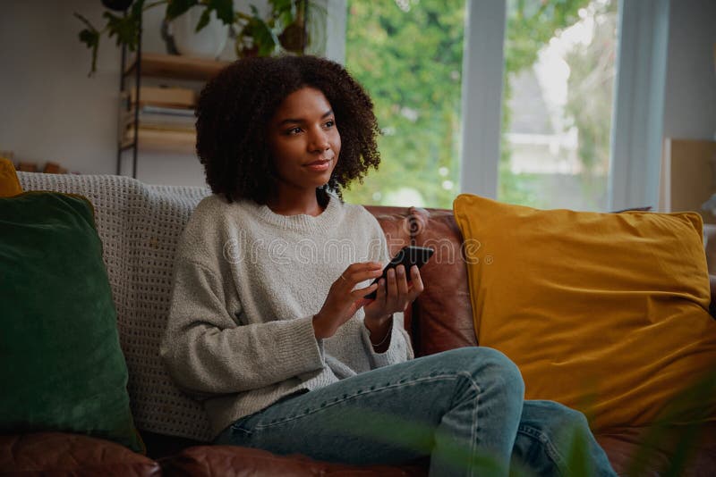 Woman thinking while holding smartphone in hand before typing message stock image