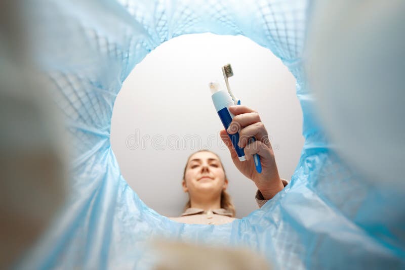 woman throwing toothbrush into trash can