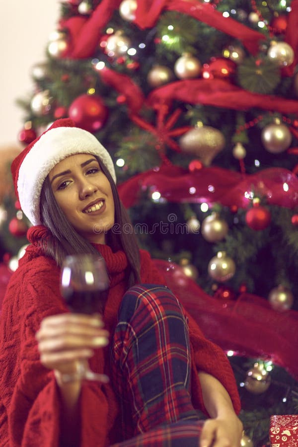 Woman toasting with red wine.holidays, winter and people concept - young woman in Santa hat by Christmas tree at home stock photos Woman toasting with red wine.holidays, winter and people concept - young woman in Santa hat by Christmas tree at home stock photos