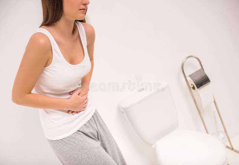 Using toilet. A young woman uses a toilet with a roll of toilet paper in his hand. Girl peeing stock images, royalty-free photos and pictures