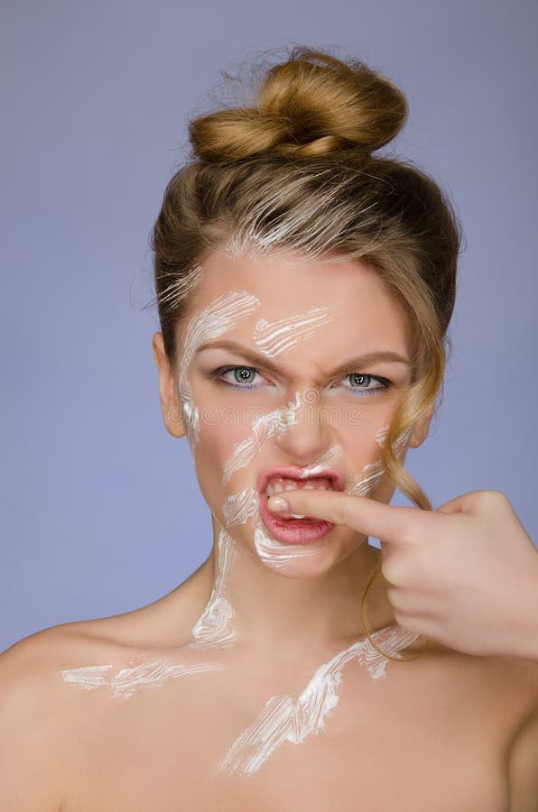 Woman in toothpaste on body cleans finger teeth