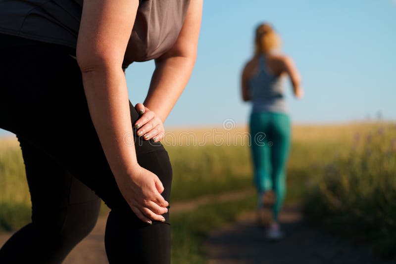 Woman touching her knee, sports injury at jogging stock photo Woman touching her knee, sports injury at jogging stock photo
