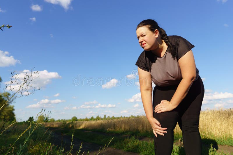 Woman touching her knee, sports injury at outdoor jogging. Health care, sports and medical concept. Woman touching her knee, sports injury at outdoor jogging. Health care, sports and medical concept