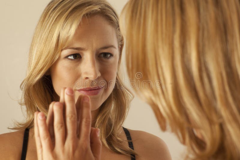Woman touching mirror while looking at reflection stock photos Woman touching mirror while looking at reflection stock photos