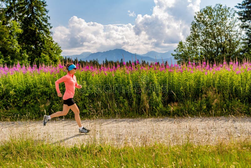 Young woman running in mountains on summer sunny day. Female athlete trail runner on country road. Sport and fitness concept outdoors in nature. Young woman running in mountains on summer sunny day. Female athlete trail runner on country road. Sport and fitness concept outdoors in nature.