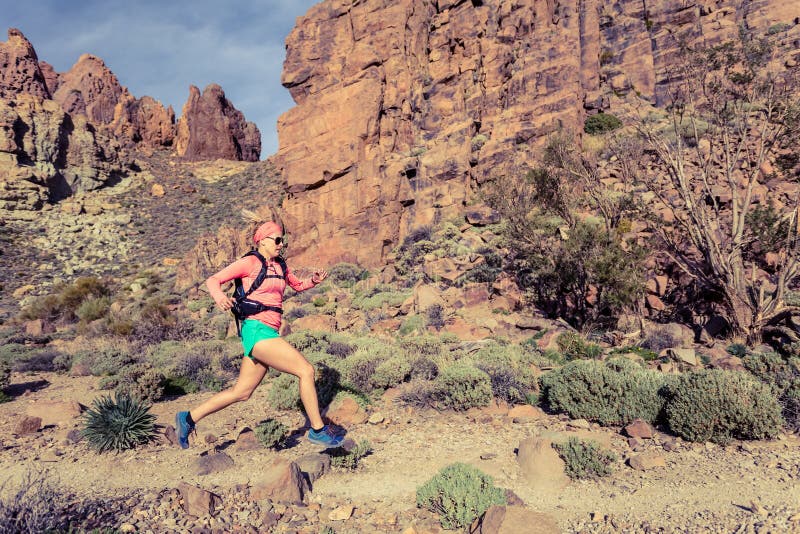 Woman trail running in mountains with backpack