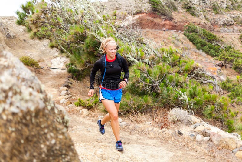 Young woman running on trail in mountains on summer day. Female runner exercising outdoors in nature on La Gomera, Canary Islands. Young woman running on trail in mountains on summer day. Female runner exercising outdoors in nature on La Gomera, Canary Islands.