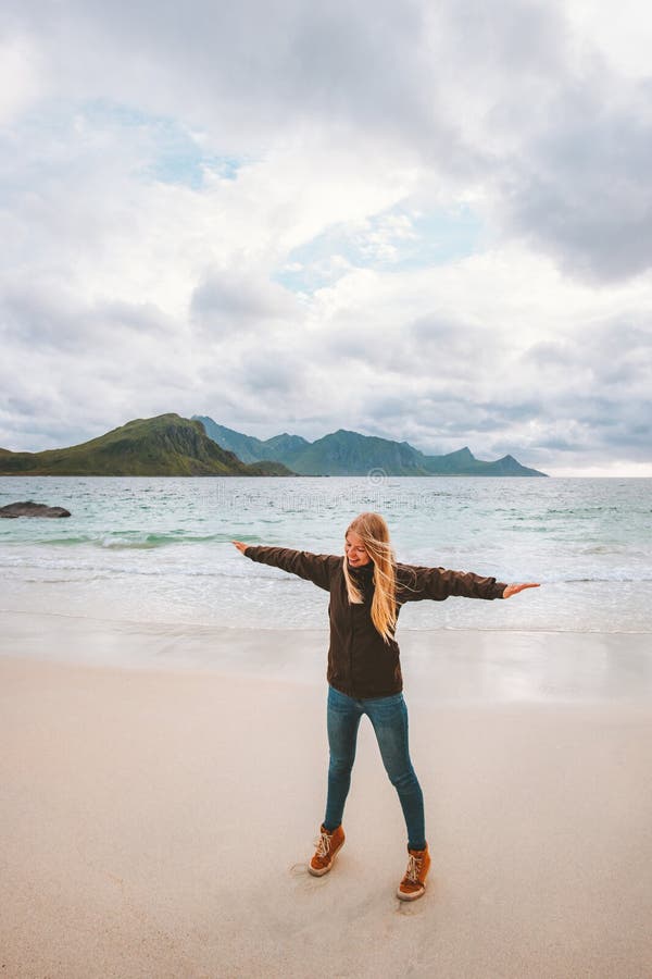 Woman traveler raised hands on sandy beach travel in Norway active vacations outdoor healthy lifestyle. Lofoten islands ocean view stock photos Woman traveler raised hands on sandy beach travel in Norway active vacations outdoor healthy lifestyle. Lofoten islands ocean view stock photos