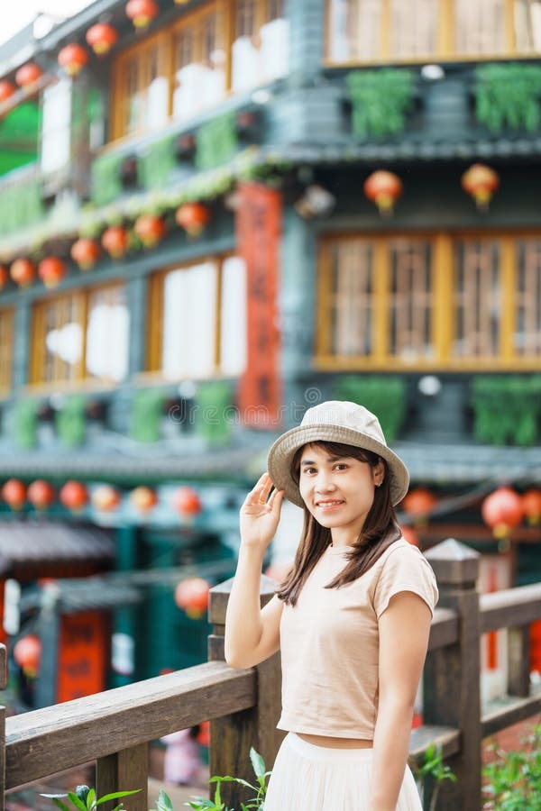Woman traveler visiting in Taiwan, Tourist with hat sightseeing in Jiufen Old Street village with Tea House background. landmark
