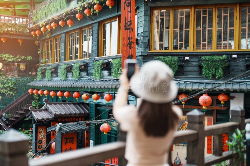Woman traveler visiting in Taiwan, Tourist taking photo and sightseeing in Jiufen Old Street village with Tea House background.