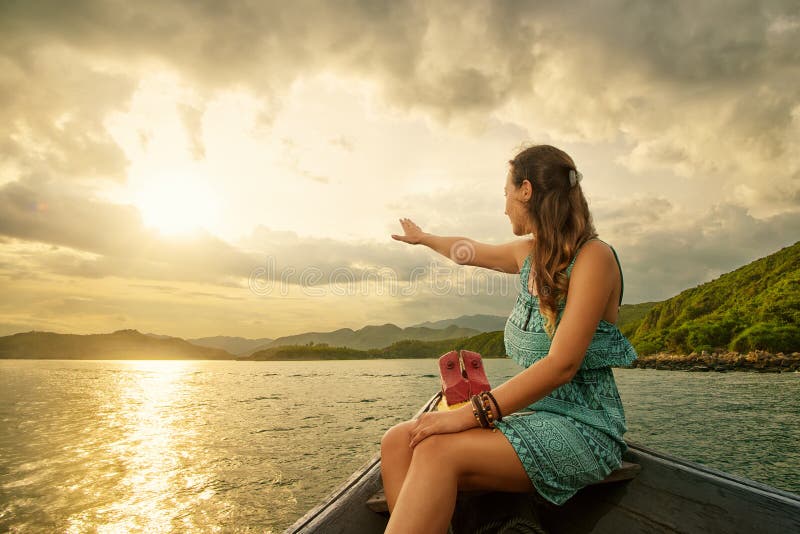 Woman traveling by boat enjoying sunset among islands.